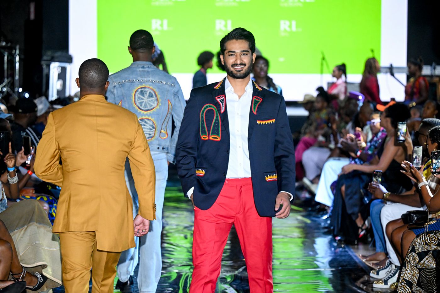Smiling model in a navy blazer and red trousers on the AFLA runway